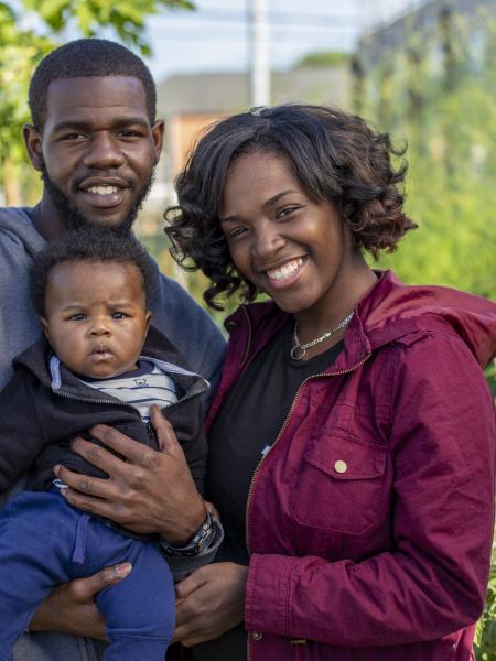 Teenage mother and father, holding their baby in a garden